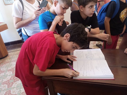 Niños firman en el libro de visitantes en la habitación de Fidel 